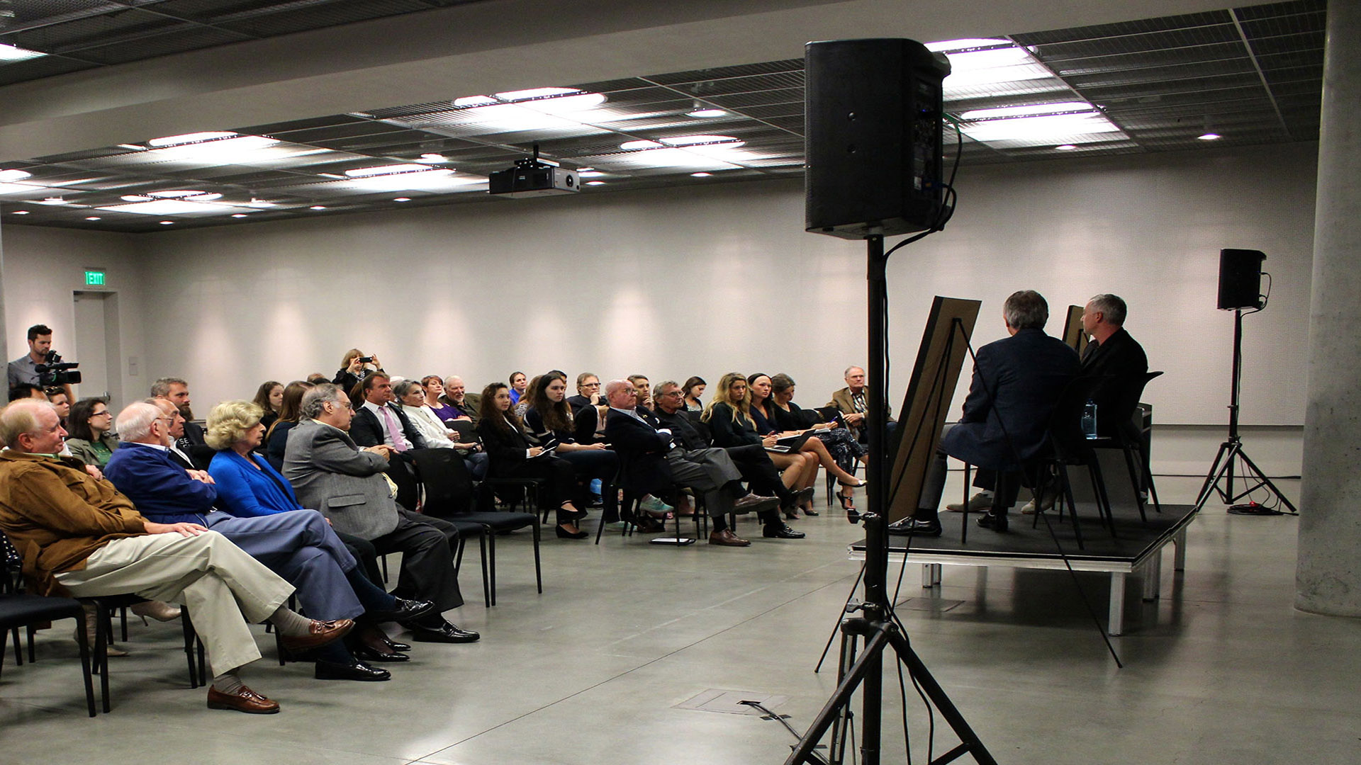 Two men presenting on stage to an audience of adults
