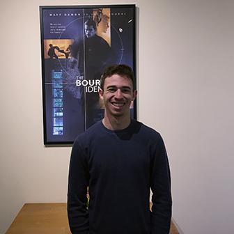 Student intern in front of poster at Captivate Entertainment